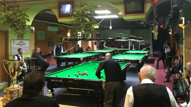 Defending champion Raymond Fung pictured on the main match table with a view of all the Prince Snooker Club's six tables in operation for the Group phase of this year's Championship - Photo  SnookerUSA.com